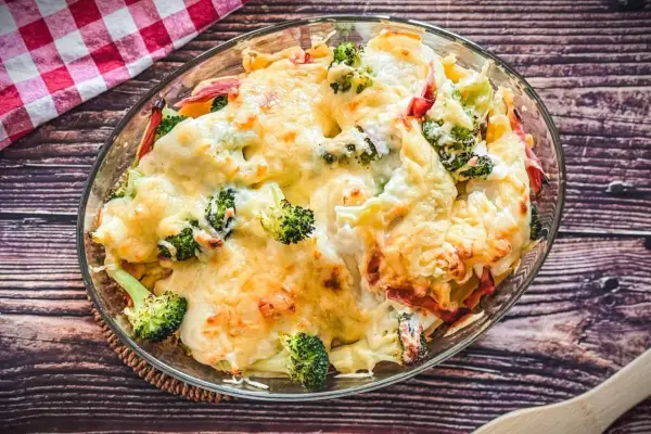 Heißer Brokkoli Nudel Auflauf mit geschmolzenem Käse in einer Glasschüssel, bereit zum Servieren.